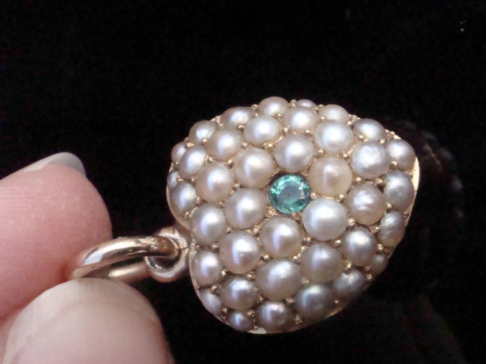 A Victorian heart-shaped 15ct yellow gold pendant encrusted with seed pearls around a single central emerald. View IV