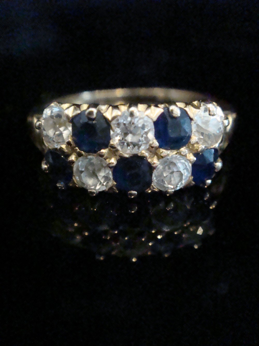 An Edwardian 18ct yellow gold ring set with two rows of alternating round blue sapphires and old-cut diamonds in a boat setting.