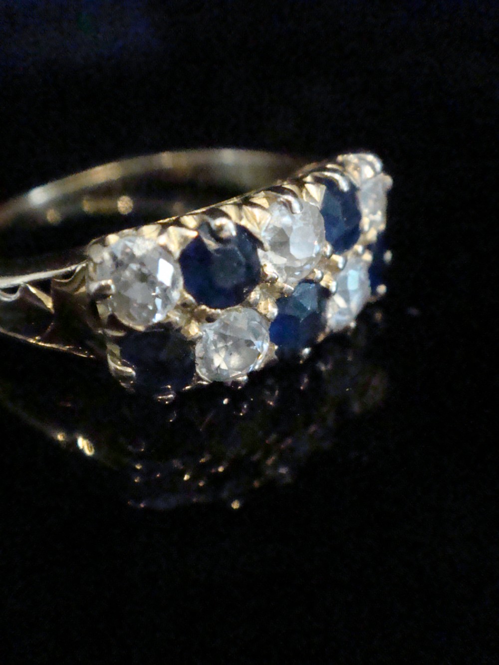 An Edwardian 18ct yellow gold ring set with two rows of alternating round blue sapphires and old-cut diamonds in a boat setting. View II