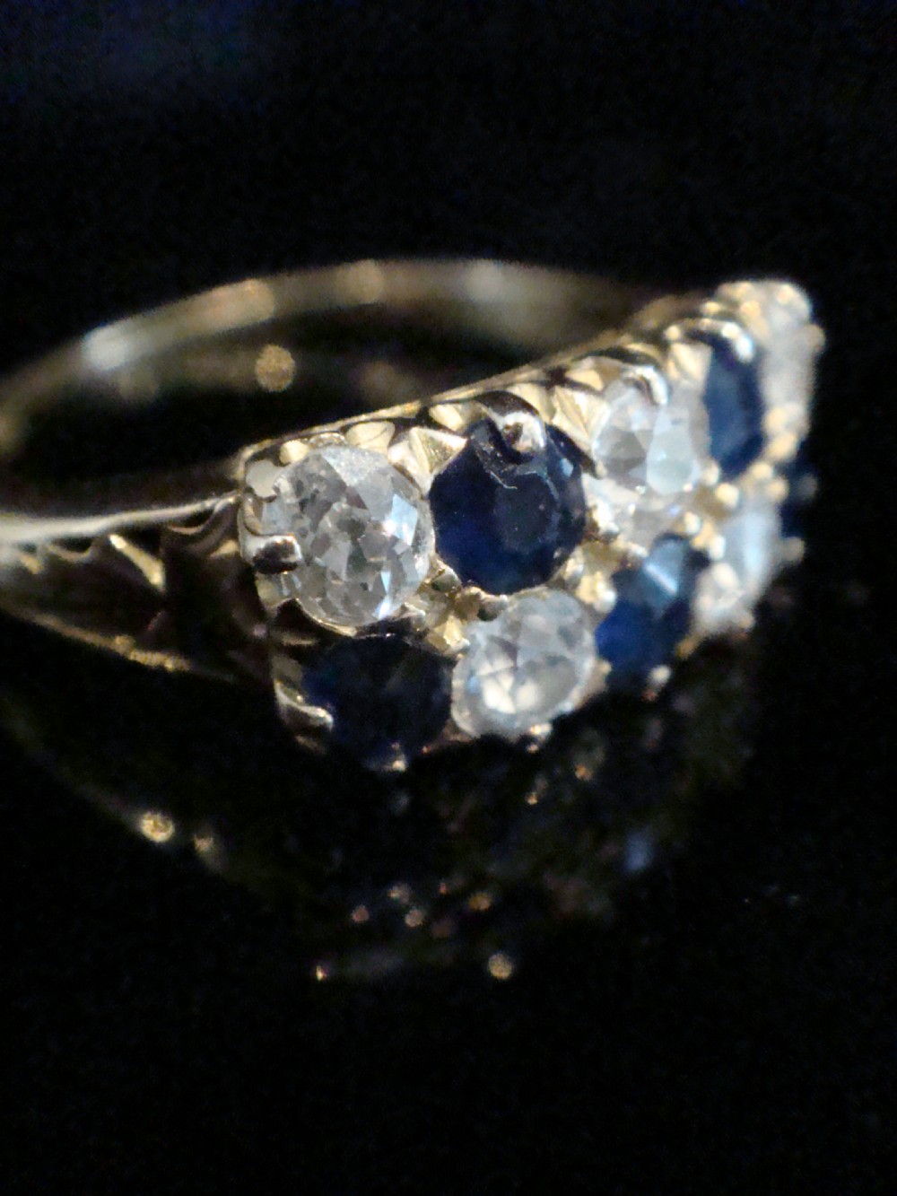 An Edwardian 18ct yellow gold ring set with two rows of alternating round blue sapphires and old-cut diamonds in a boat setting. View III