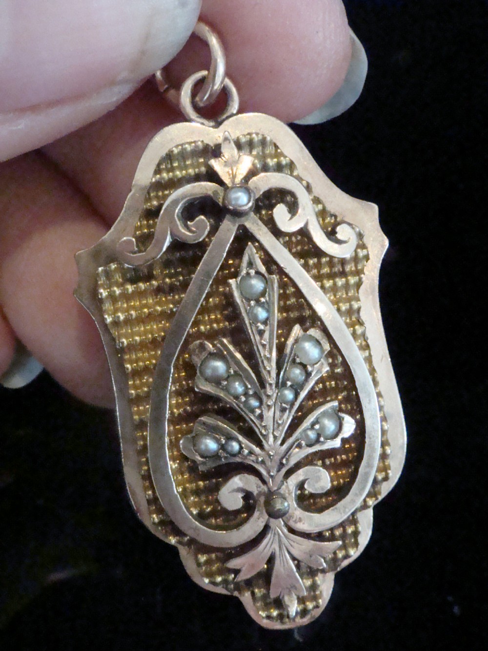 A Victorian rose gold locket featuring textured engine-turned patterning and a central leaf motif inset with small seed pearls. View IV