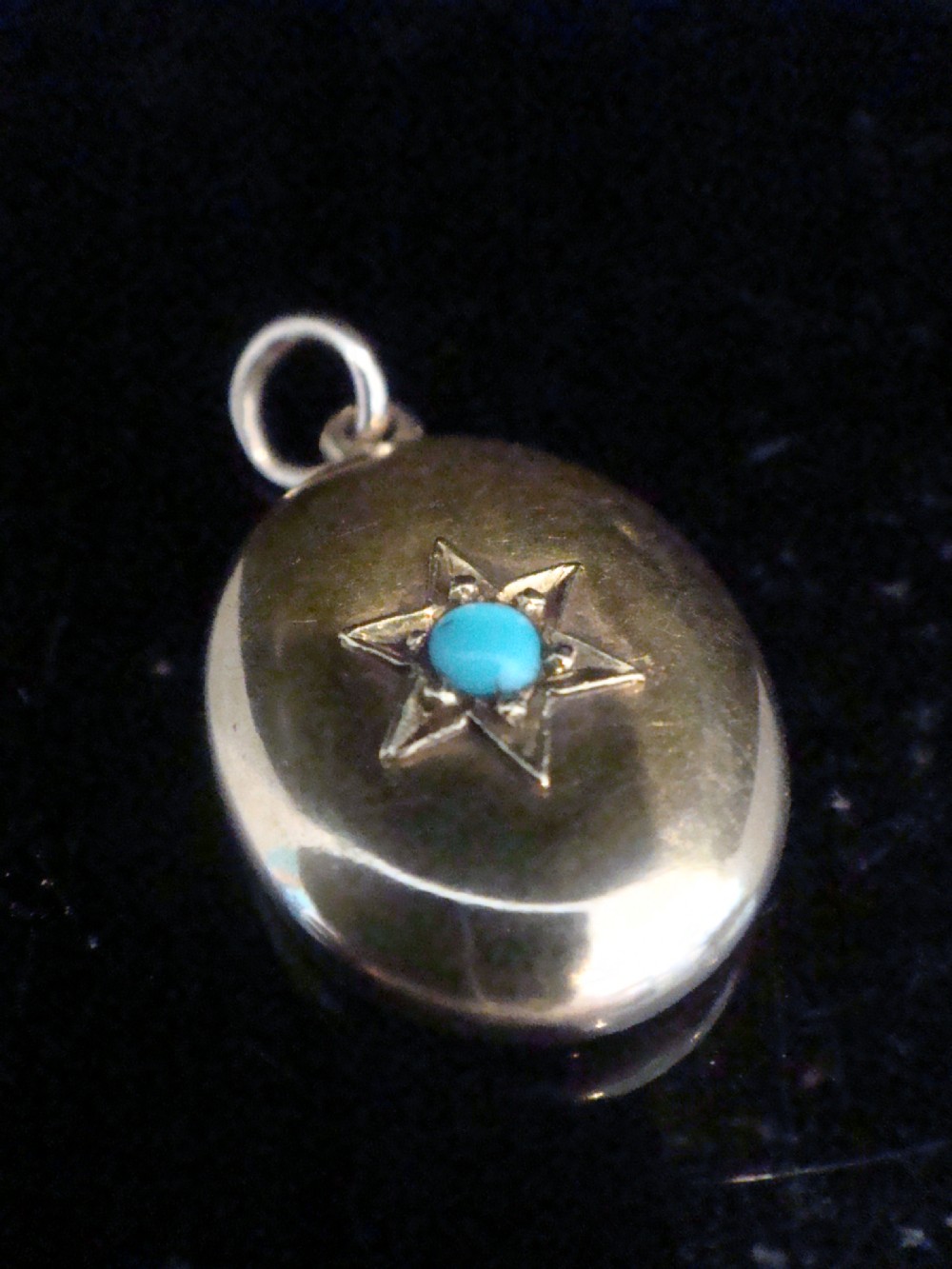 An oval 15ct yellow gold locket featuring an engraved star setting inset with a round turquoise cabochon. View II