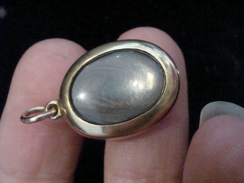An oval 15ct yellow gold locket featuring an engraved star setting inset with a round turquoise cabochon. View III