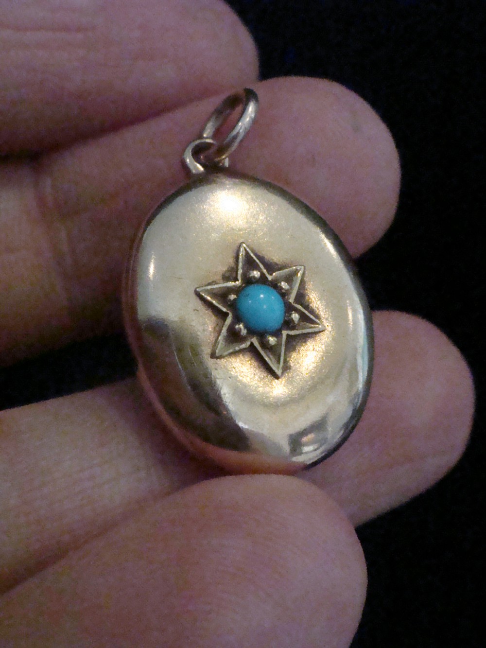 An oval 15ct yellow gold locket featuring an engraved star setting inset with a round turquoise cabochon. View IV