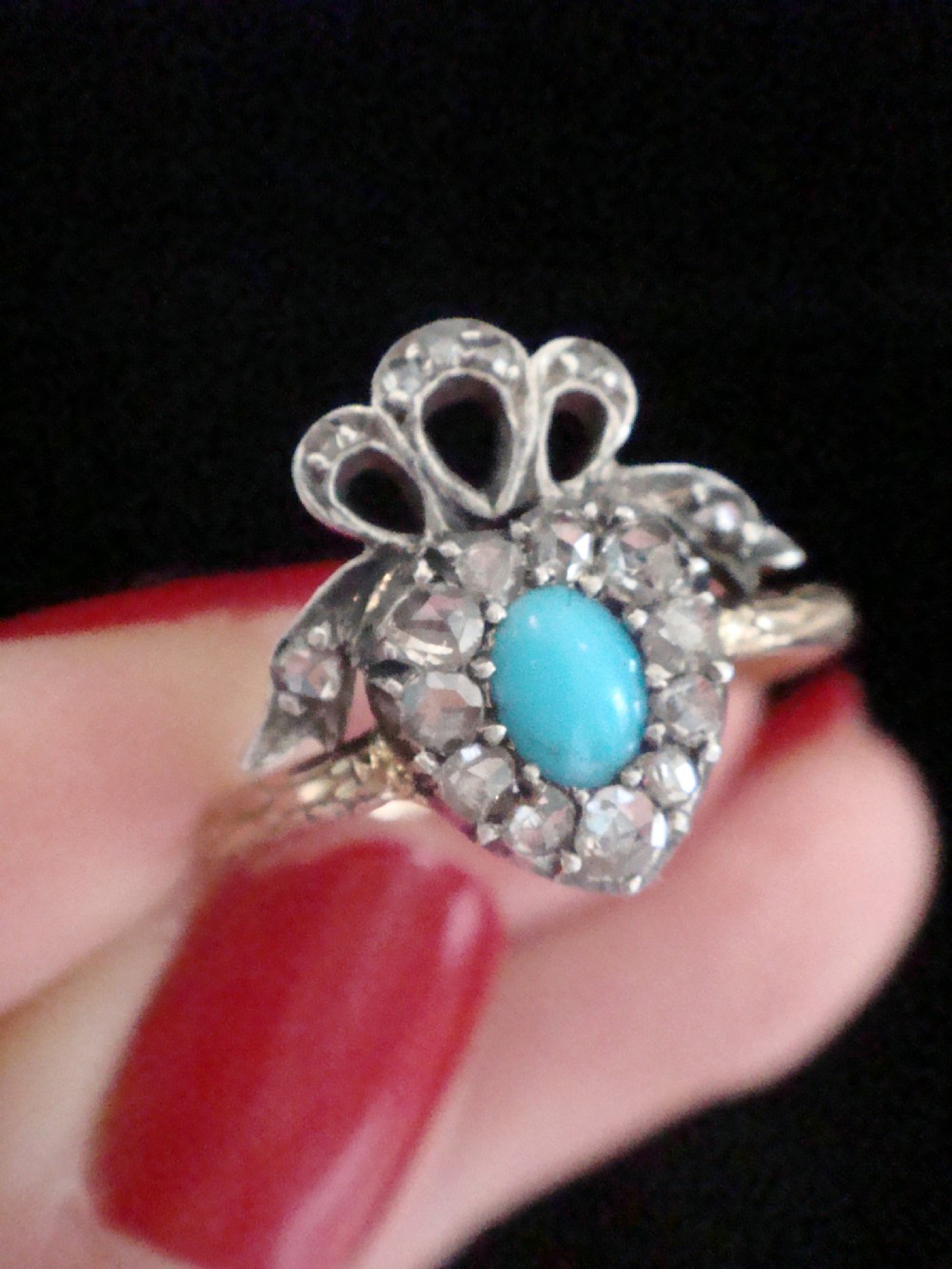 An antique heart-shaped ring featuring a central turquoise cabochon framed by rose-cut diamonds and topped with a diamond ribbon bow motif on a thin gold band. View III