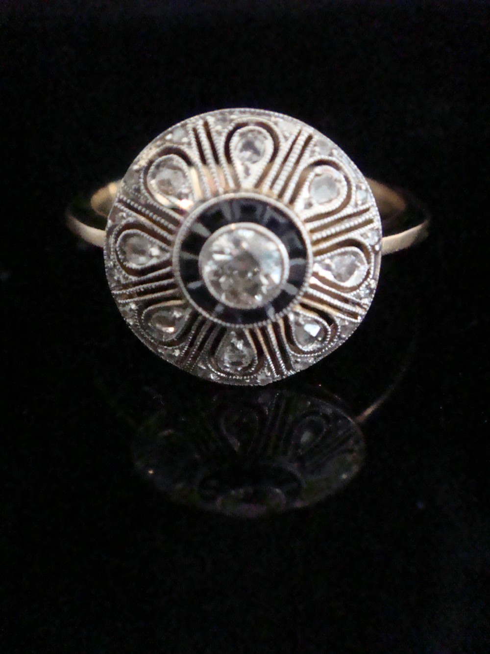 An Art Deco round target ring featuring a central diamond encircled by calibre-cut sapphires and radiating openwork set with rose-cut diamonds. View II