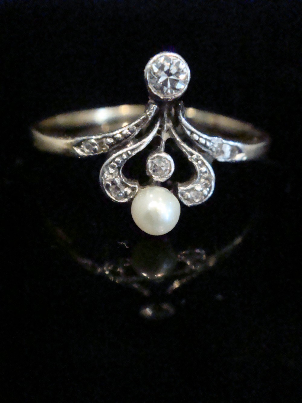 A French Edwardian 18ct gold and platinum ring featuring a central natural pearl set below a tiara motif with old-cut diamonds.