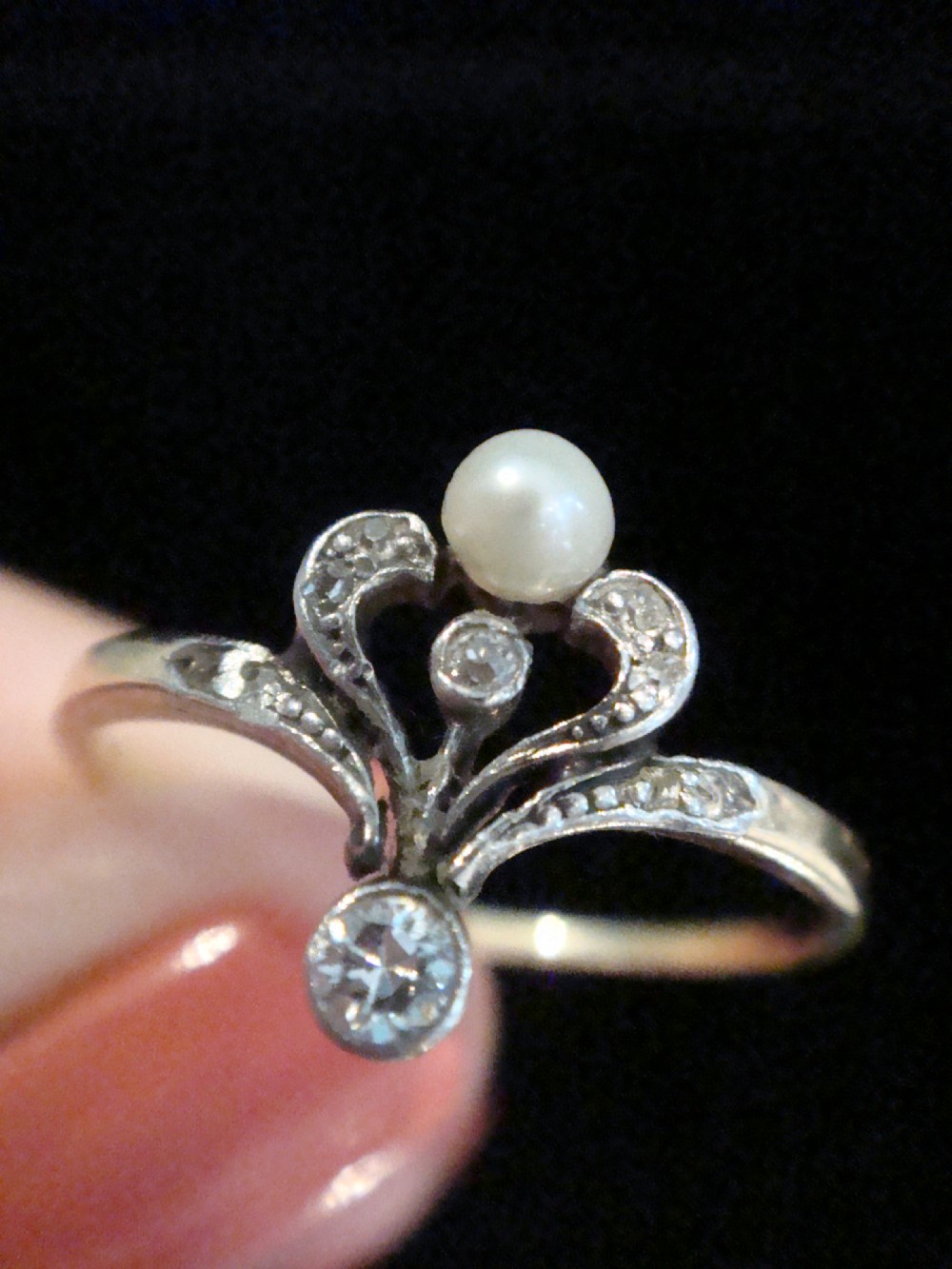 A French Edwardian 18ct gold and platinum ring featuring a central natural pearl set below a tiara motif with old-cut diamonds. View IV