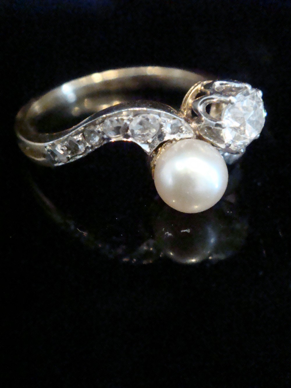 An Edwardian French 18ct yellow gold toi et moi ring set with a single cultured pearl and an old-cut diamond on a curved bypass band with accent diamonds. View II