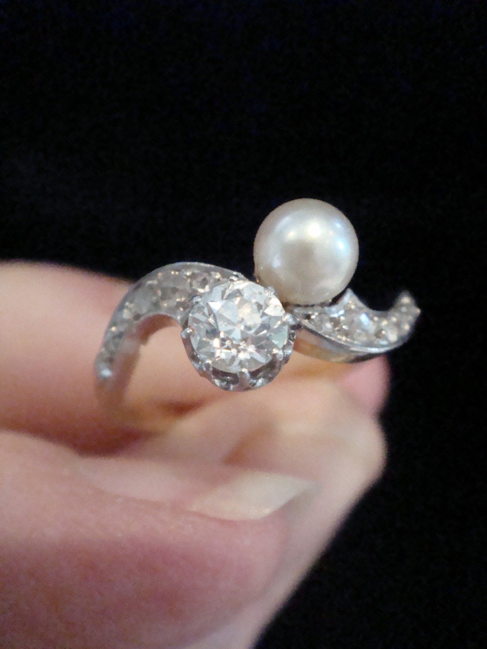 An Edwardian French 18ct yellow gold toi et moi ring set with a single cultured pearl and an old-cut diamond on a curved bypass band with accent diamonds. View IV