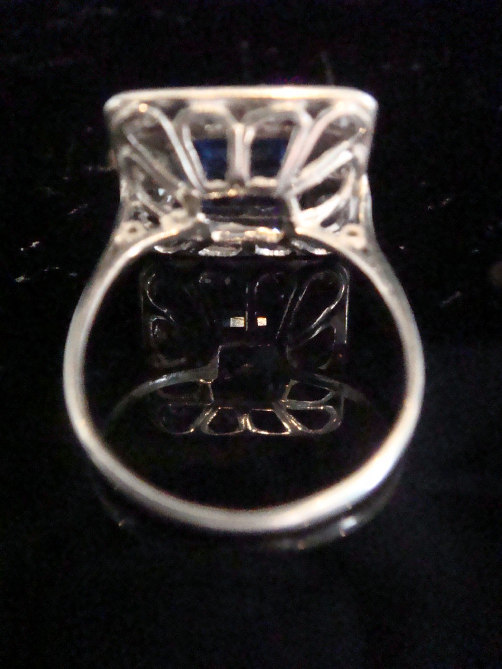 An Edwardian platinum and gold square cluster ring featuring a blue synthetic sapphire surrounded by old cut diamonds with a millegrain edge. View V