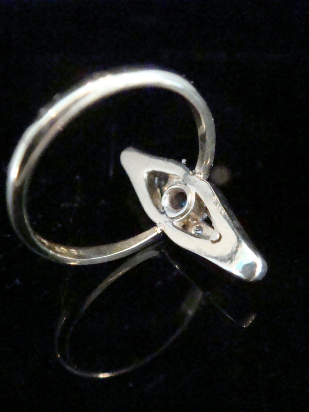An Edwardian marquise-shaped ring featuring a central round blue sapphire encircled by old cut diamonds set in platinum atop an 18ct yellow gold band. View III