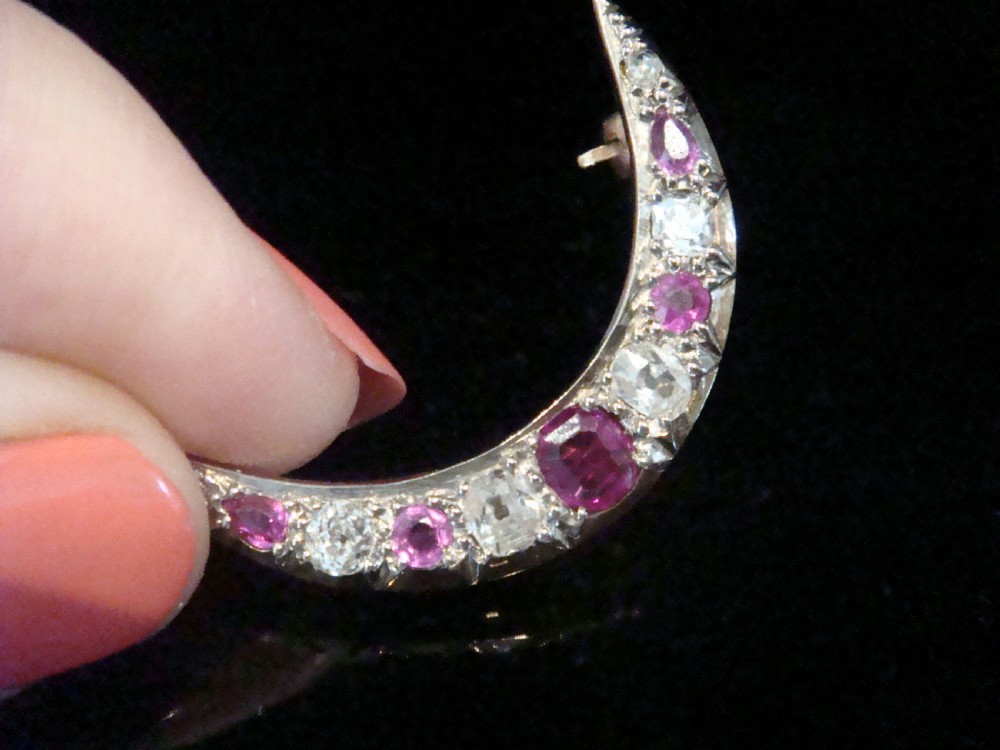 An Edwardian 18ct yellow gold crescent brooch featuring alternating natural red rubies and clear diamonds. View II