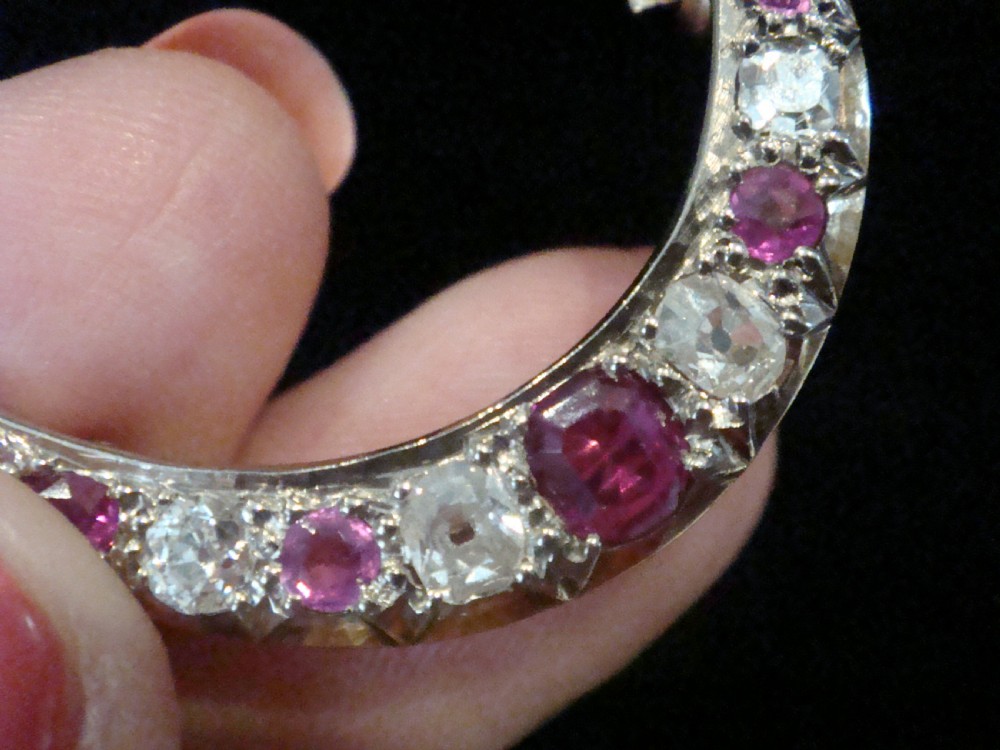 An Edwardian 18ct yellow gold crescent brooch featuring alternating natural red rubies and clear diamonds. View IV
