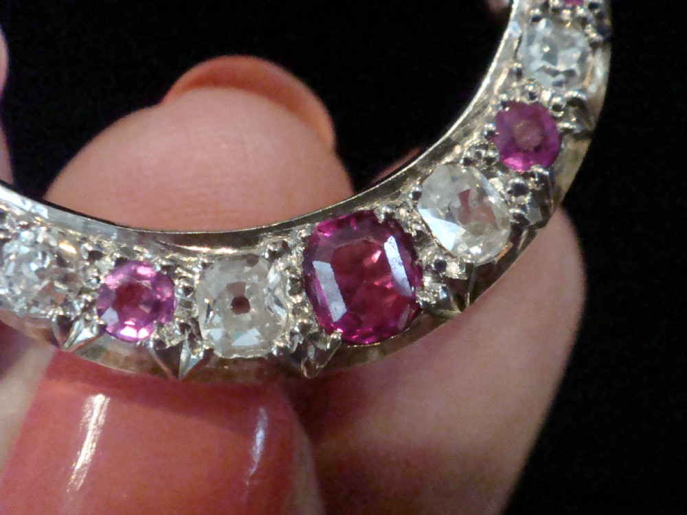 An Edwardian 18ct yellow gold crescent brooch featuring alternating natural red rubies and clear diamonds. View VI