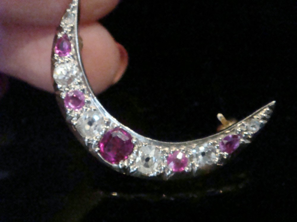 An Edwardian 18ct yellow gold crescent brooch featuring alternating natural red rubies and clear diamonds. View IX