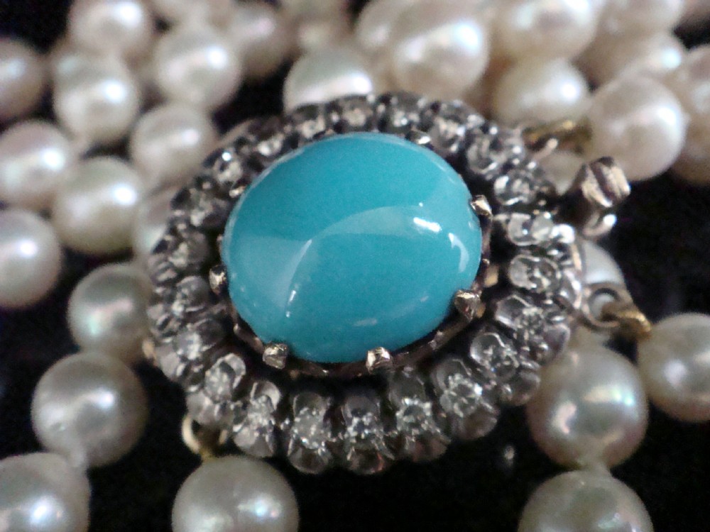 A strand of white cultured pearls fastened with an Edwardian clasp set with a central turquoise cabochon surrounded by a halo of diamonds. View II