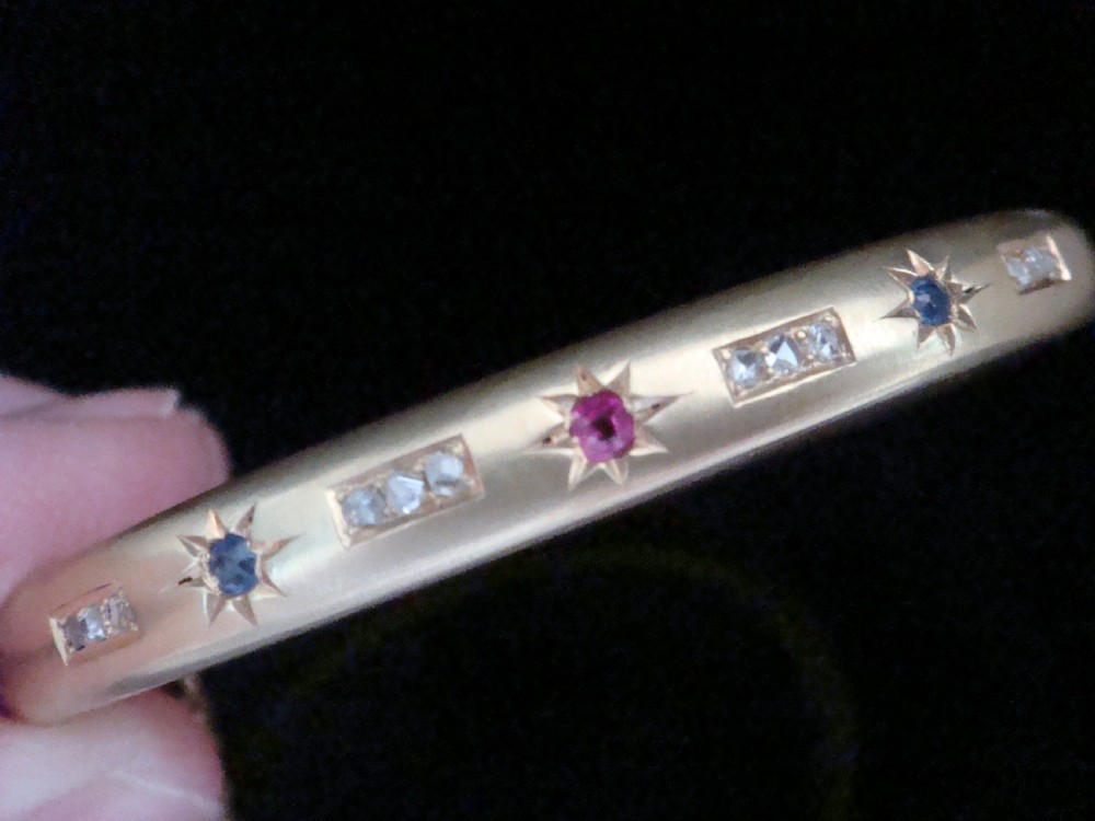 A matte 15ct yellow gold hinged bangle featuring star-set sapphires and rubies alongside rose-cut diamond accents. View II