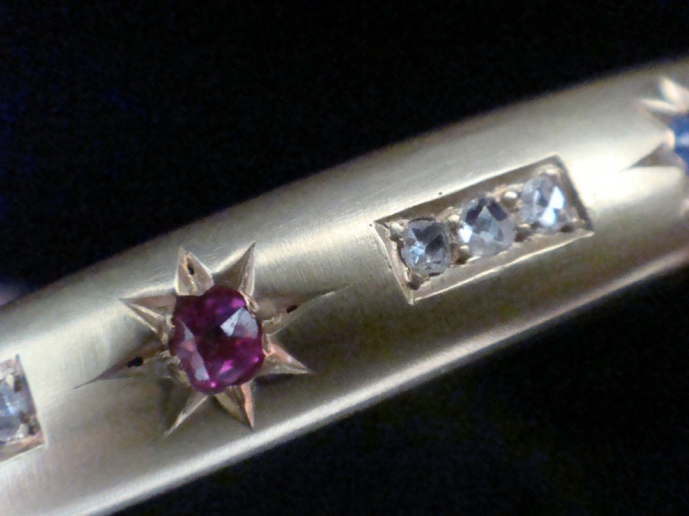A matte 15ct yellow gold hinged bangle featuring star-set sapphires and rubies alongside rose-cut diamond accents. View III