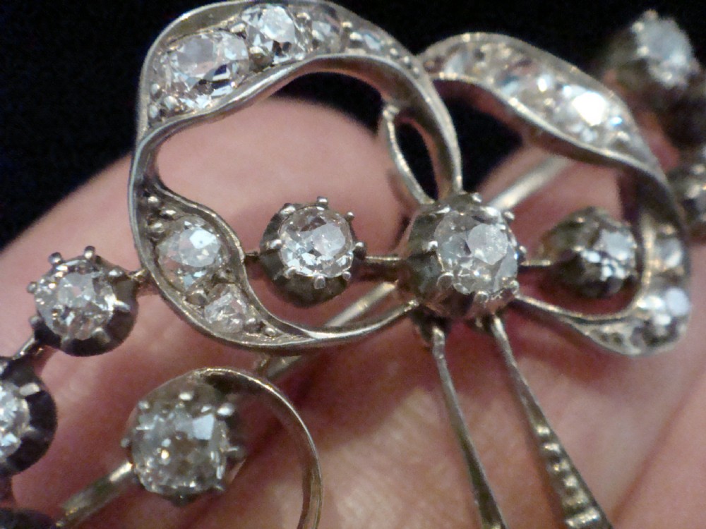 An Edwardian silver and gold bow brooch set with round diamonds and two hanging oval blue sapphires. View V
