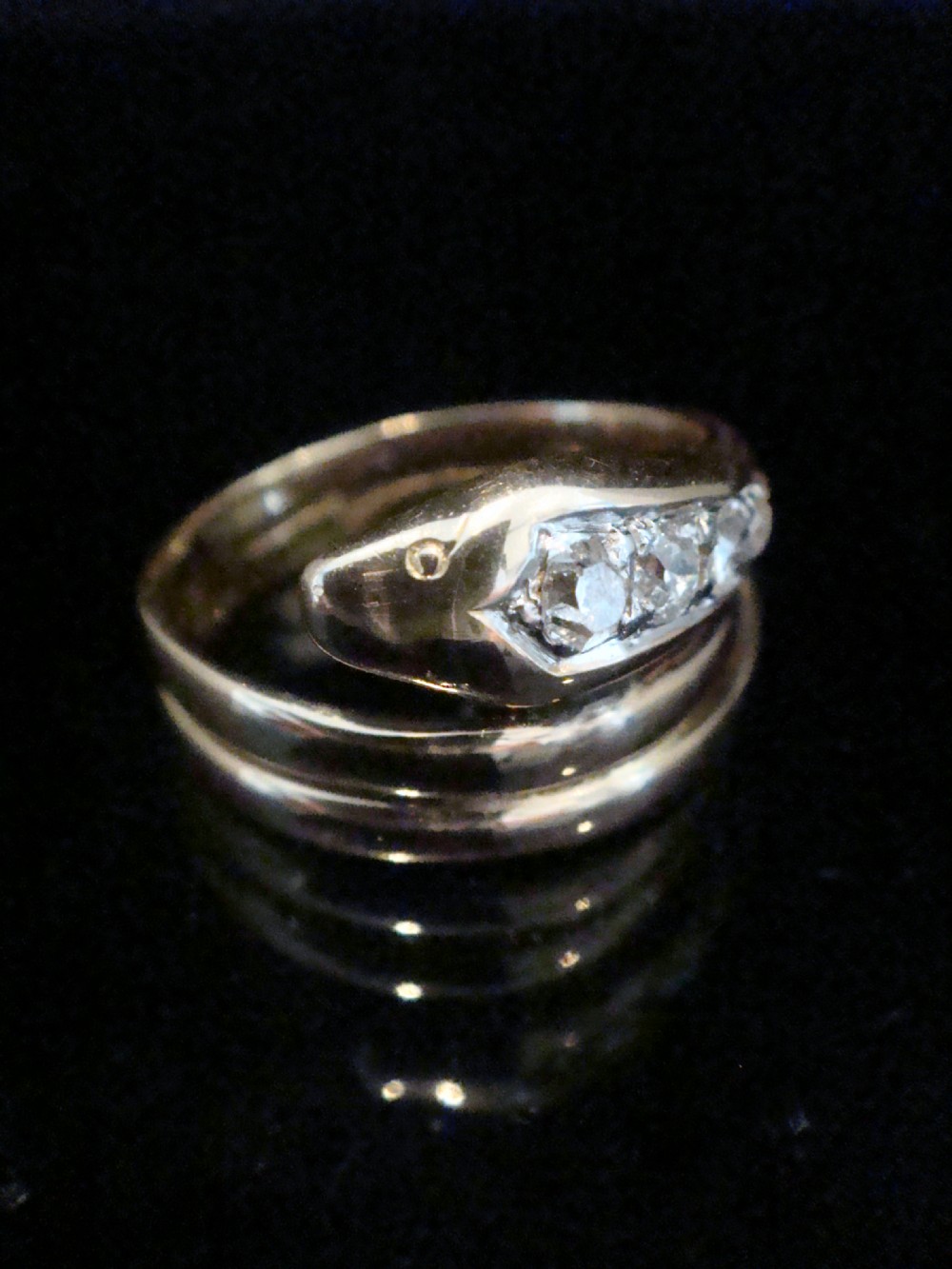 A Victorian 18ct gold snake ring featuring a coiled band set with a line of five graduated old cut diamonds along the serpent head. View II