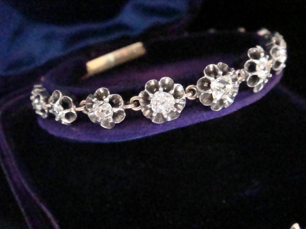Victorian silver and gold link bracelet set with a row of flower-shaped cluster links containing round diamonds.