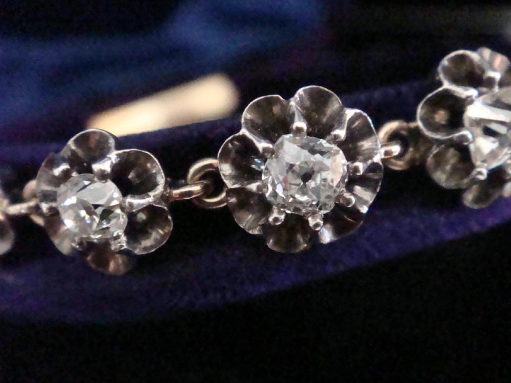 Victorian silver and gold link bracelet set with a row of flower-shaped cluster links containing round diamonds. View IV