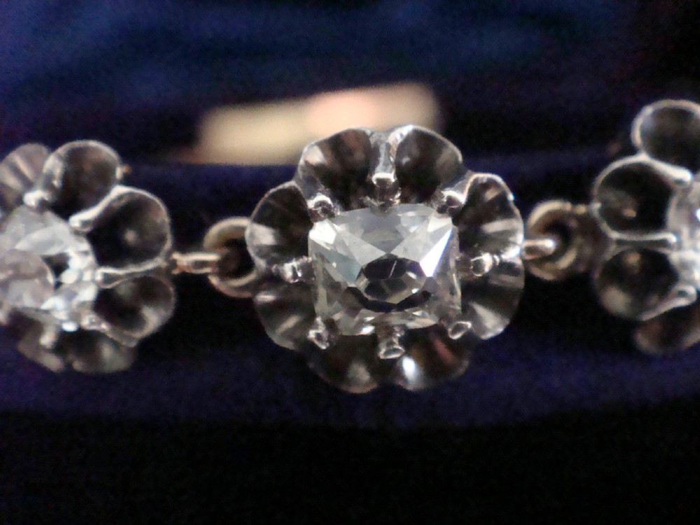 Victorian silver and gold link bracelet set with a row of flower-shaped cluster links containing round diamonds. View V