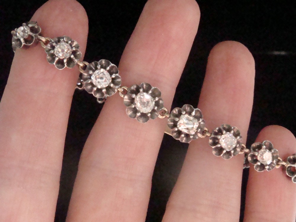 Victorian silver and gold link bracelet set with a row of flower-shaped cluster links containing round diamonds. View VII
