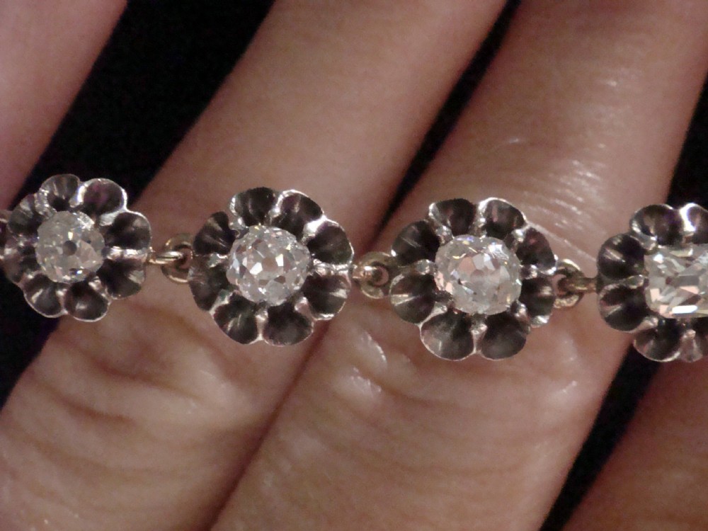 Victorian silver and gold link bracelet set with a row of flower-shaped cluster links containing round diamonds. View IX