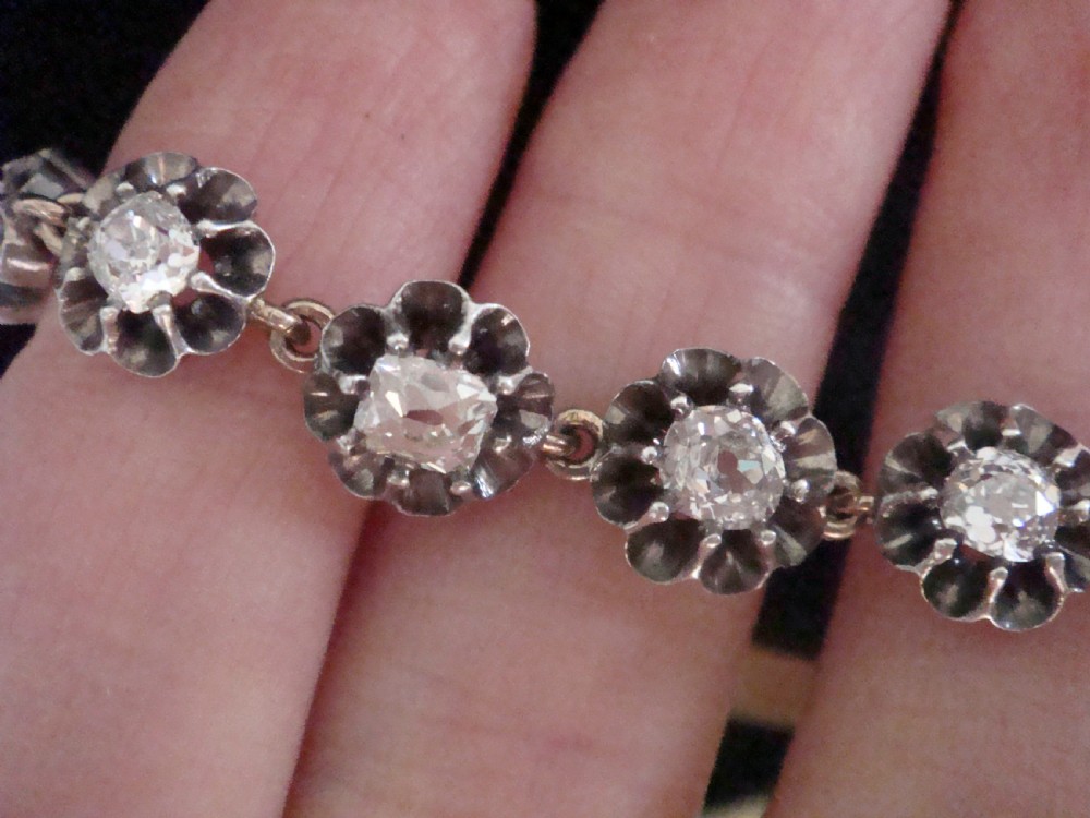 Victorian silver and gold link bracelet set with a row of flower-shaped cluster links containing round diamonds. View X