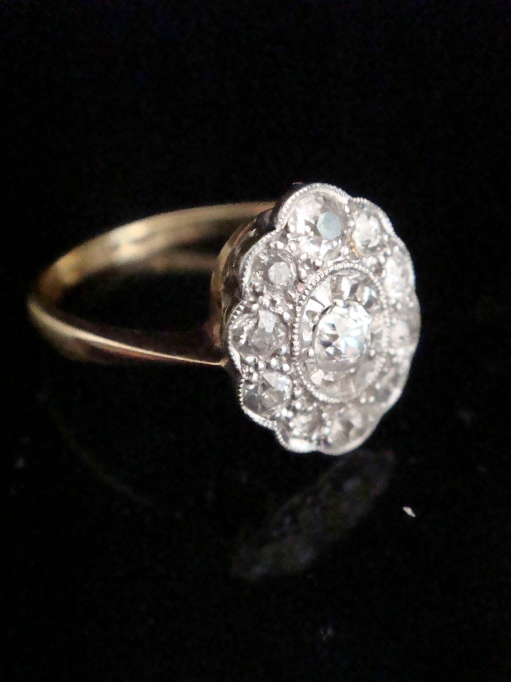An Edwardian 18ct yellow gold and platinum ring featuring a scalloped cluster head pave-set with old cut diamonds and millegrain detailing. View II