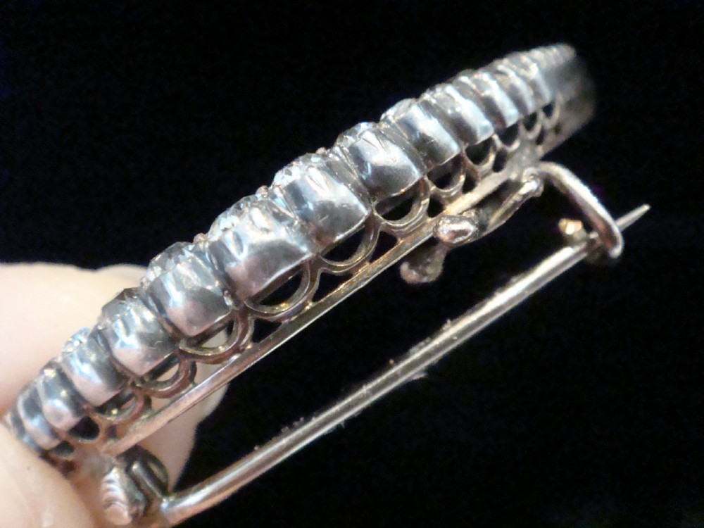An Edwardian crescent moon brooch featuring a graduated row of round diamonds mounted in a curved precious metal setting with a pin back. View III