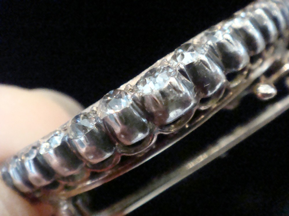 An Edwardian crescent moon brooch featuring a graduated row of round diamonds mounted in a curved precious metal setting with a pin back. View IV