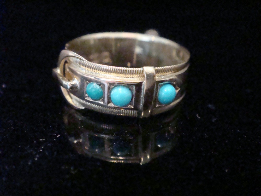 A Victorian 15ct yellow gold band ring shaped like a belt buckle, inlaid with three round turquoise cabochons and featuring detailed textured borders.