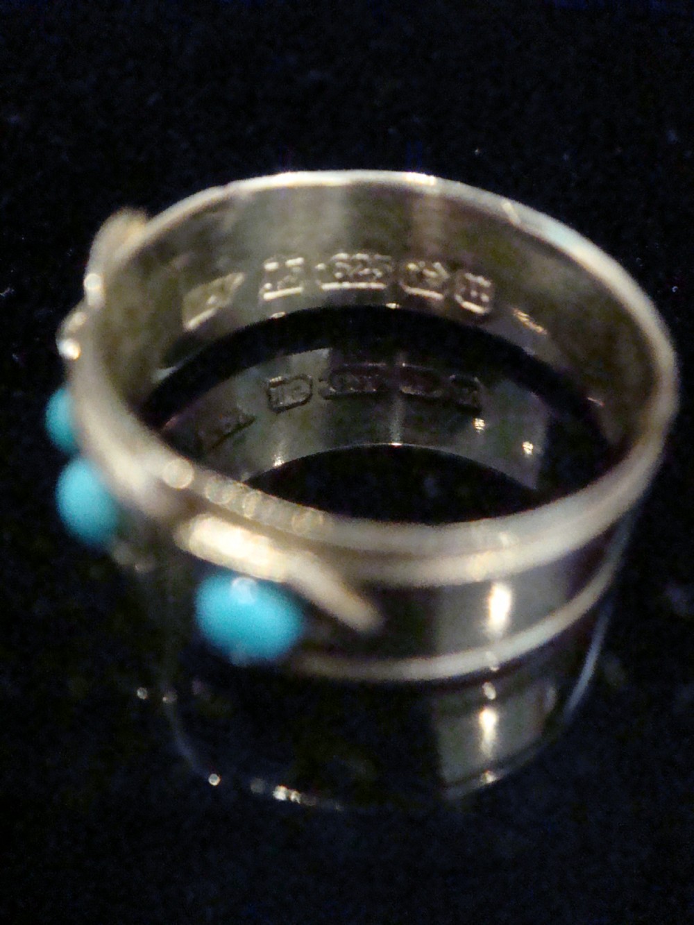 A Victorian 15ct yellow gold band ring shaped like a belt buckle, inlaid with three round turquoise cabochons and featuring detailed textured borders. View II