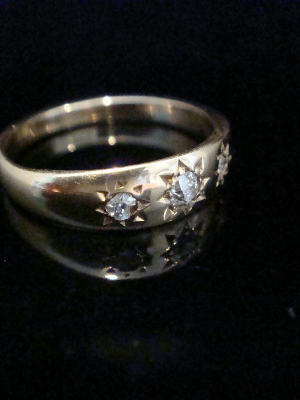 An Edwardian 18ct yellow gold ring featuring three old cut diamonds set flush within starburst star engravings. View II
