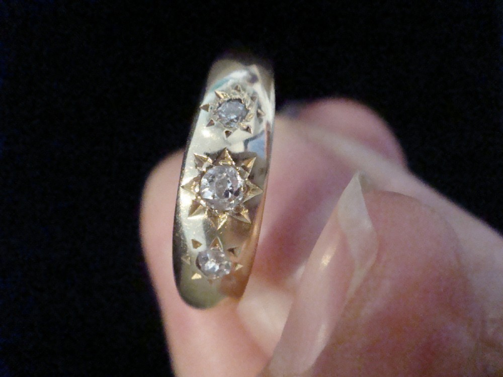 An Edwardian 18ct yellow gold ring featuring three old cut diamonds set flush within starburst star engravings. View III