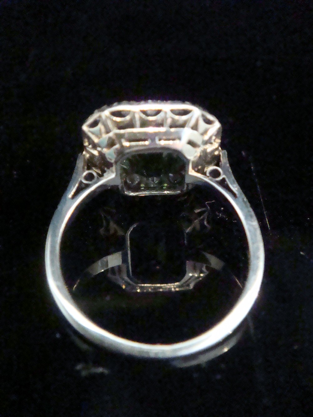 An Art Deco cluster ring featuring a central emerald-cut green tourmaline surrounded by a halo of diamonds set in platinum. View IV