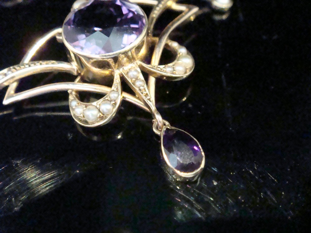 An Edwardian Art Nouveau 15ct gold lavaliere necklace featuring an openwork frame set with a round central amethyst, seed pearls, and a pear-cut dangling amethyst drop. View II