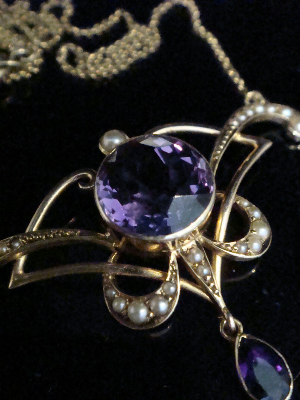 An Edwardian Art Nouveau 15ct gold lavaliere necklace featuring an openwork frame set with a round central amethyst, seed pearls, and a pear-cut dangling amethyst drop. View III
