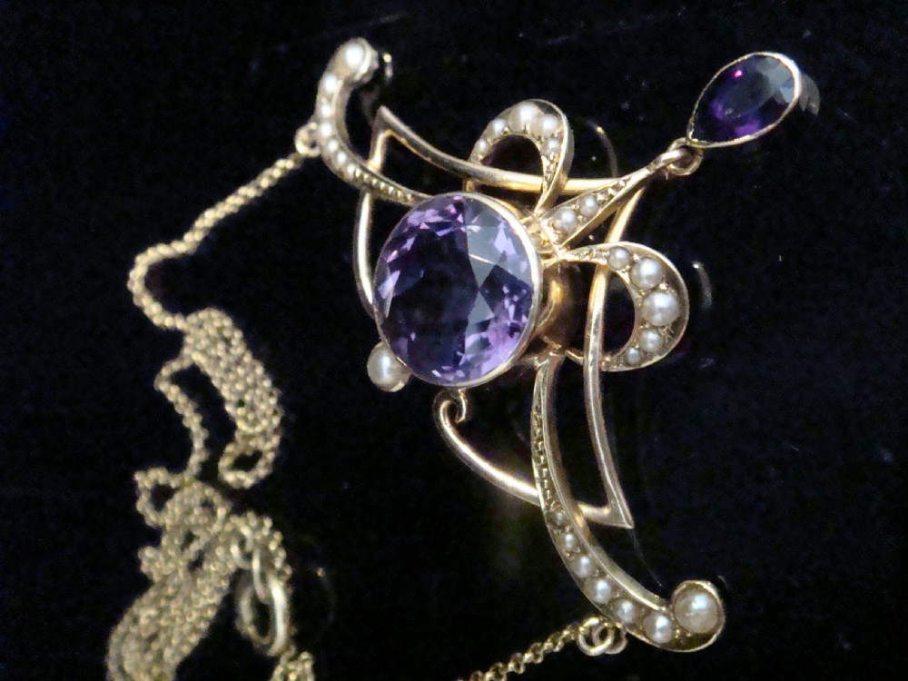 An Edwardian Art Nouveau 15ct gold lavaliere necklace featuring an openwork frame set with a round central amethyst, seed pearls, and a pear-cut dangling amethyst drop. View IV