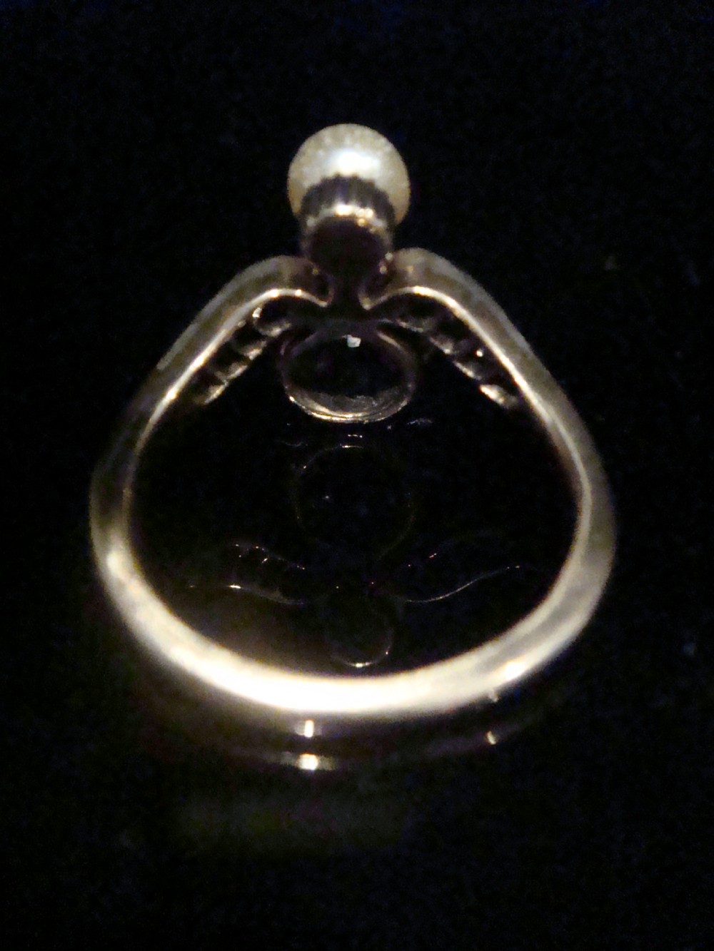 An Edwardian 18ct yellow gold ring featuring a central round ruby surrounded by old-cut diamonds with accent shoulder diamonds and a natural pearl. View IV