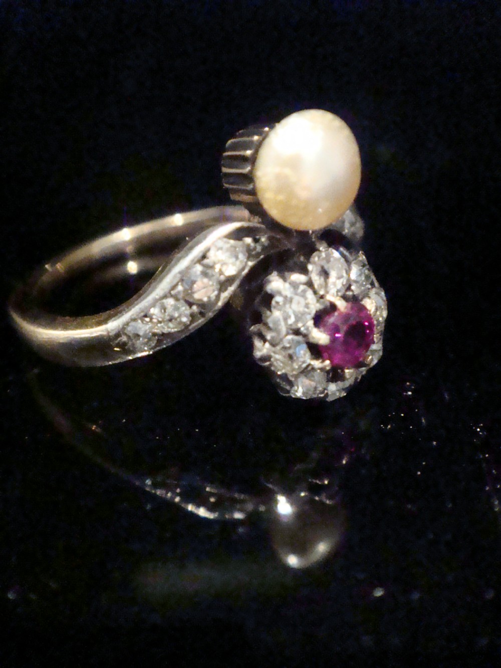 An Edwardian 18ct yellow gold ring featuring a central round ruby surrounded by old-cut diamonds with accent shoulder diamonds and a natural pearl. View III