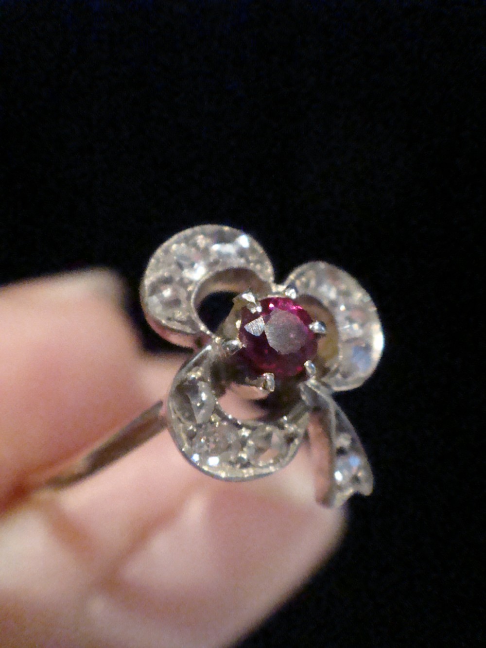 An Edwardian 18ct yellow gold ring featuring a three-leaf clover motif set with rose cut diamonds and a central round ruby. View II