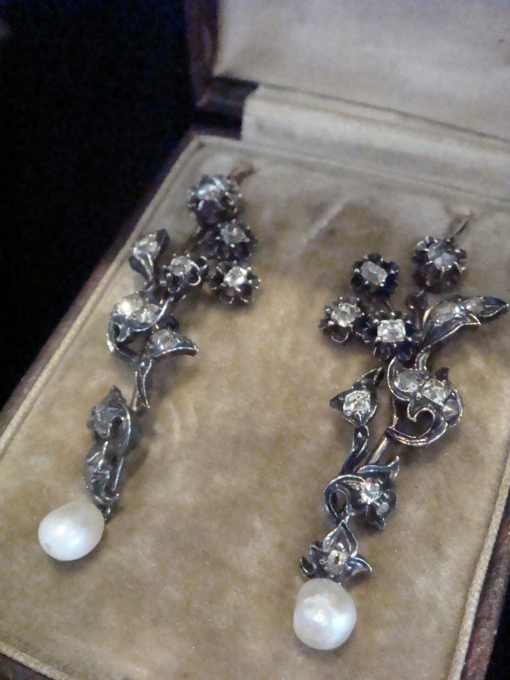 A pair of antique yellow gold and silver drop earrings featuring foliate diamond sprays and natural pearl drops presented inside a velvet box. View II