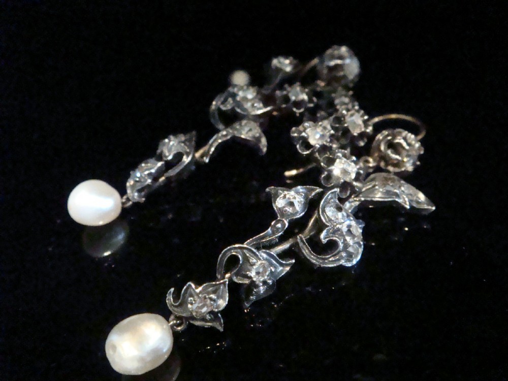 A pair of antique yellow gold and silver drop earrings featuring foliate diamond sprays and natural pearl drops presented inside a velvet box. View VI