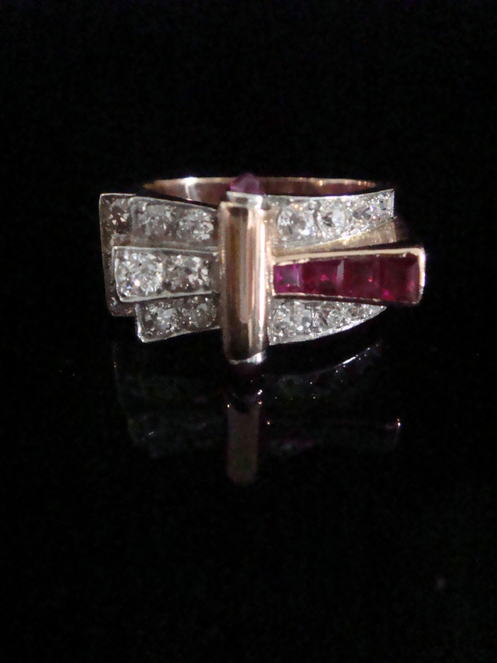 An 18ct gold Retro Modern tank ring featuring geometric diamond shoulders and a channel of calibre-cut red rubies.