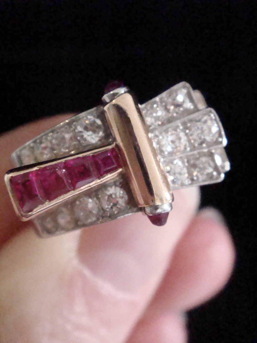 An 18ct gold Retro Modern tank ring featuring geometric diamond shoulders and a channel of calibre-cut red rubies. View V