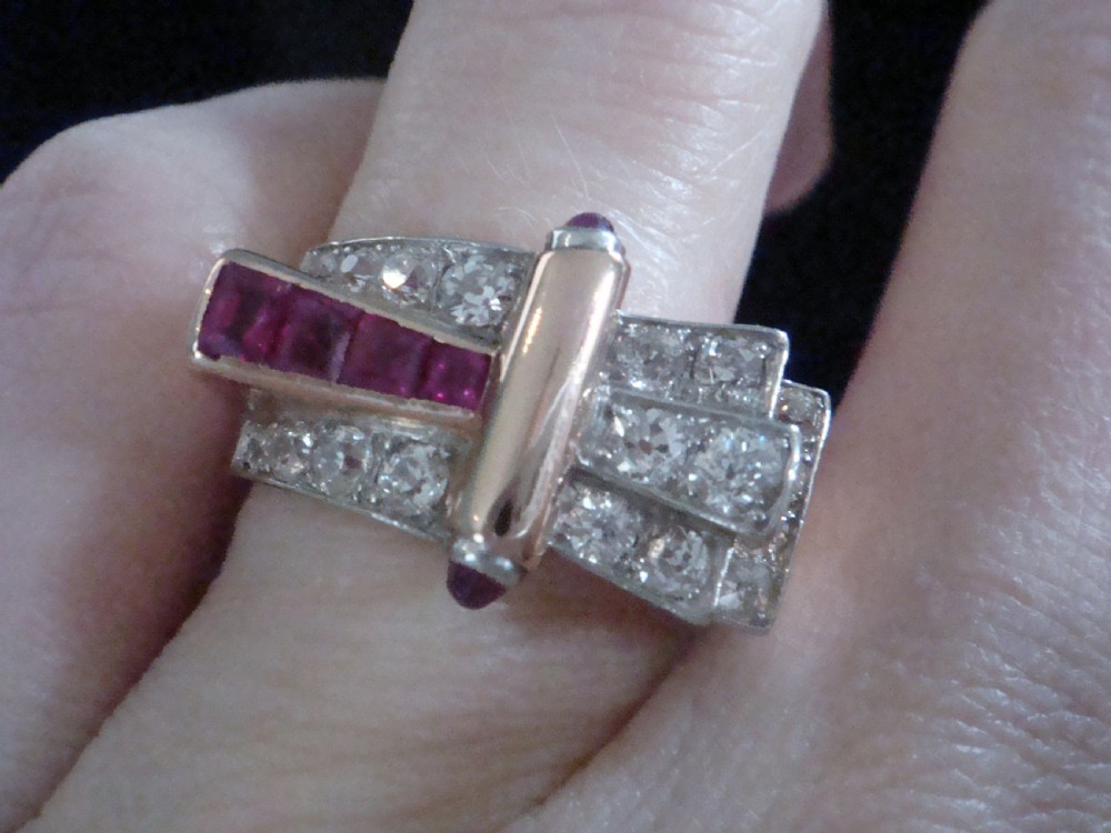 An 18ct gold Retro Modern tank ring featuring geometric diamond shoulders and a channel of calibre-cut red rubies. View VII